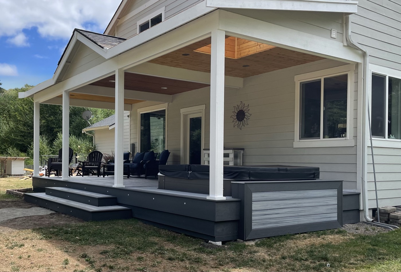 Covered composite deck with white posts, wood ceiling, and built-in hot tub
