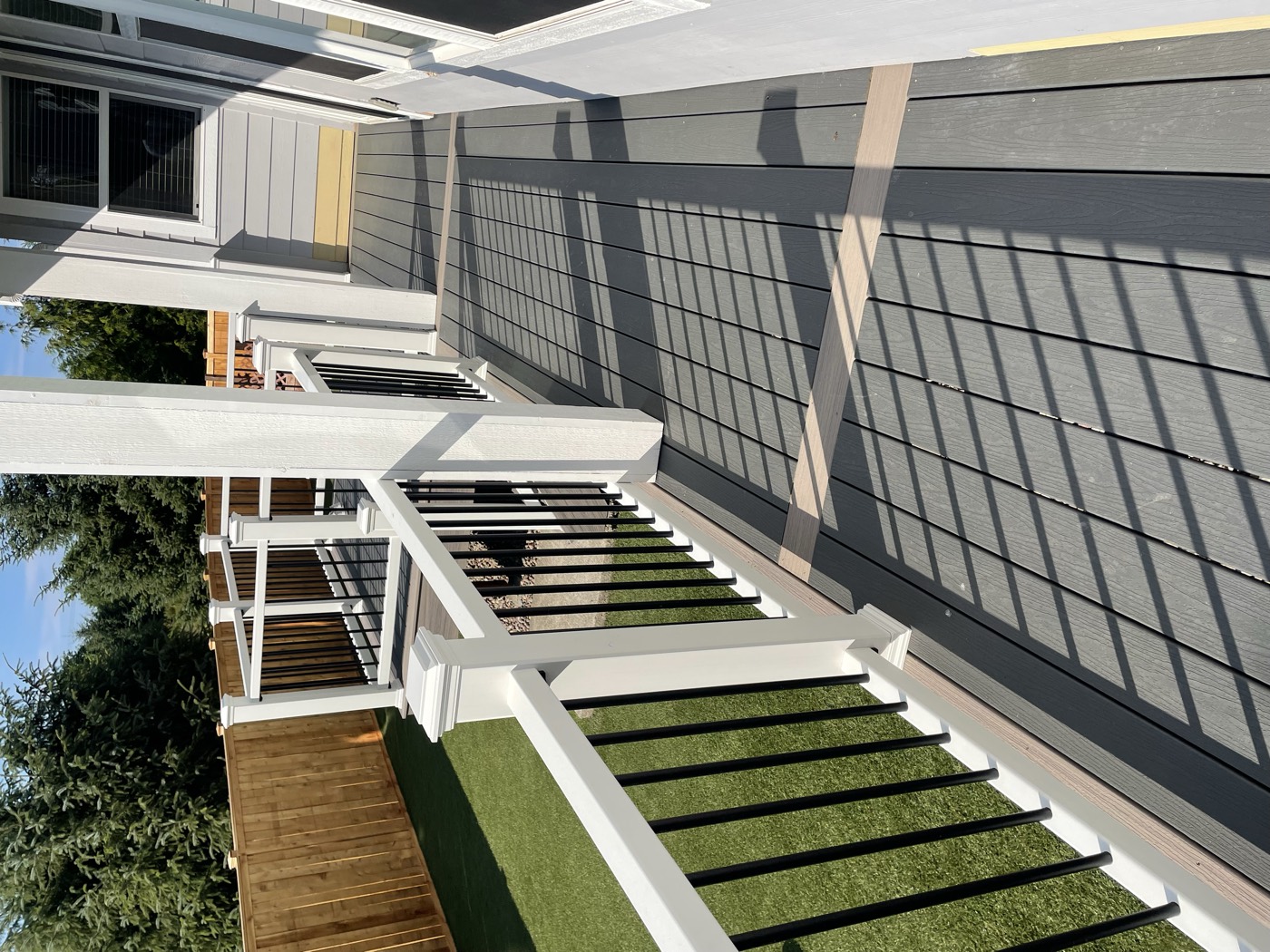 Long composite porch with white and black railing overlooking a fenced backyard