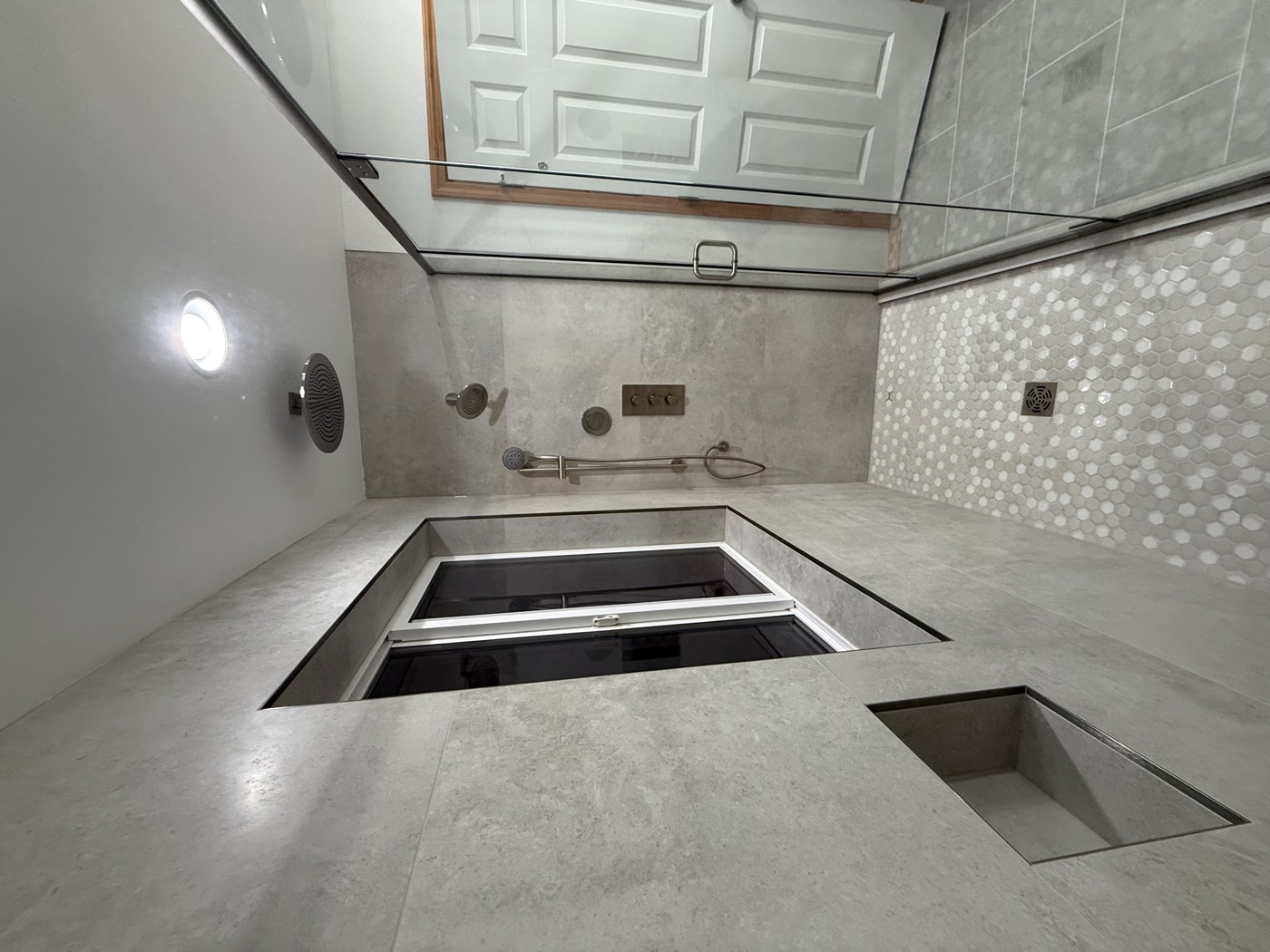 Walk-in shower with stone-look walls, rain shower head, window, and penny-tile floor