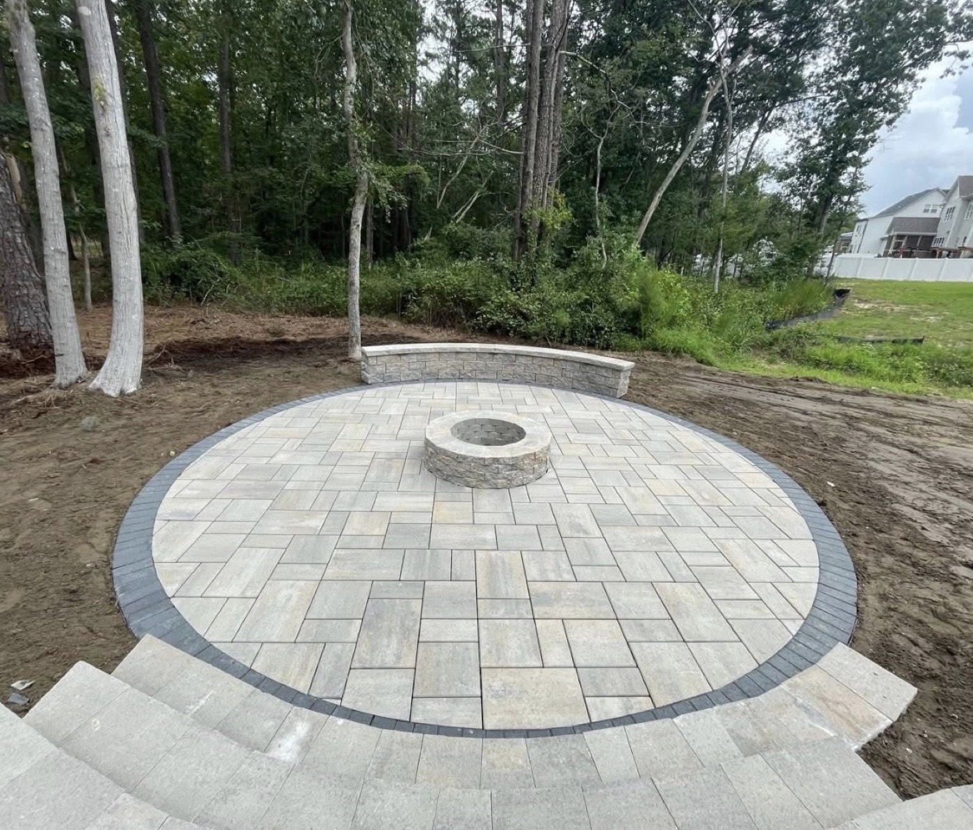 Circular paver patio with stone fire pit and curved seating wall