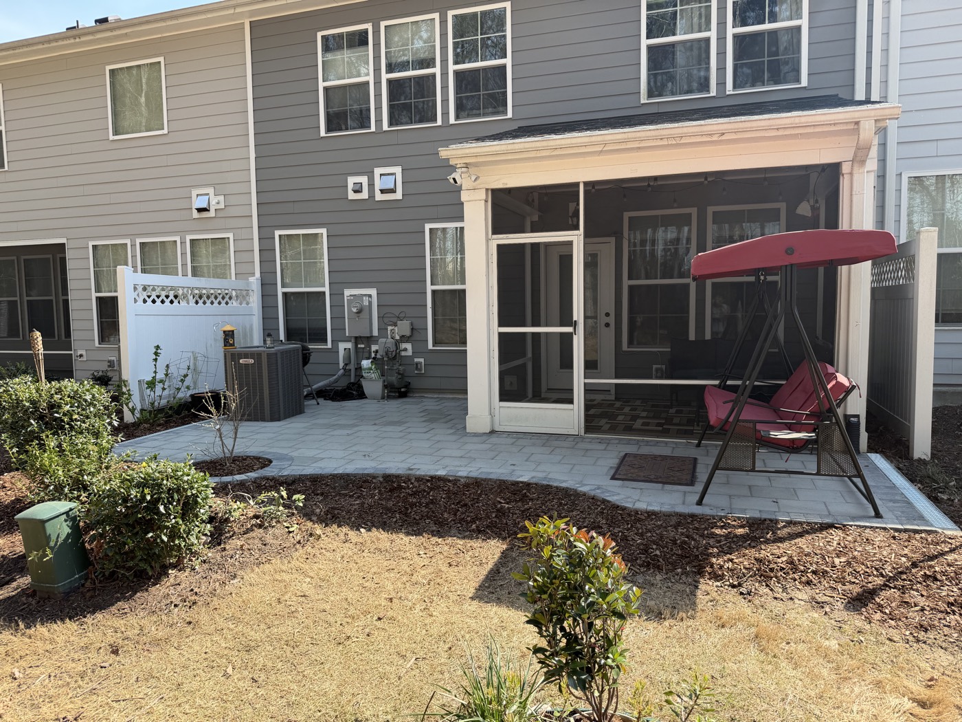 Paver patio and fresh landscaping behind a screened porch